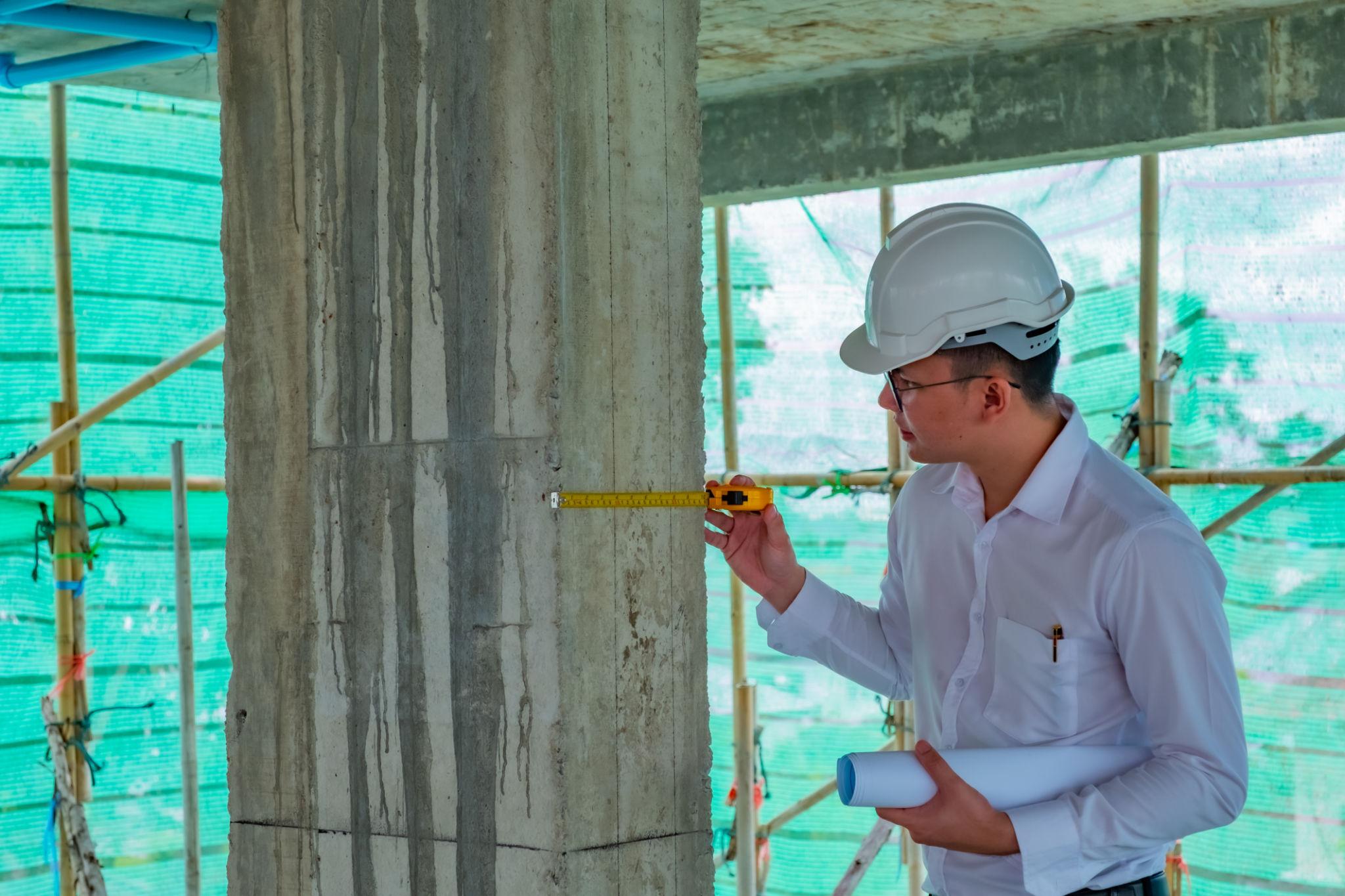 Quality assurance professional measuring concrete column on site